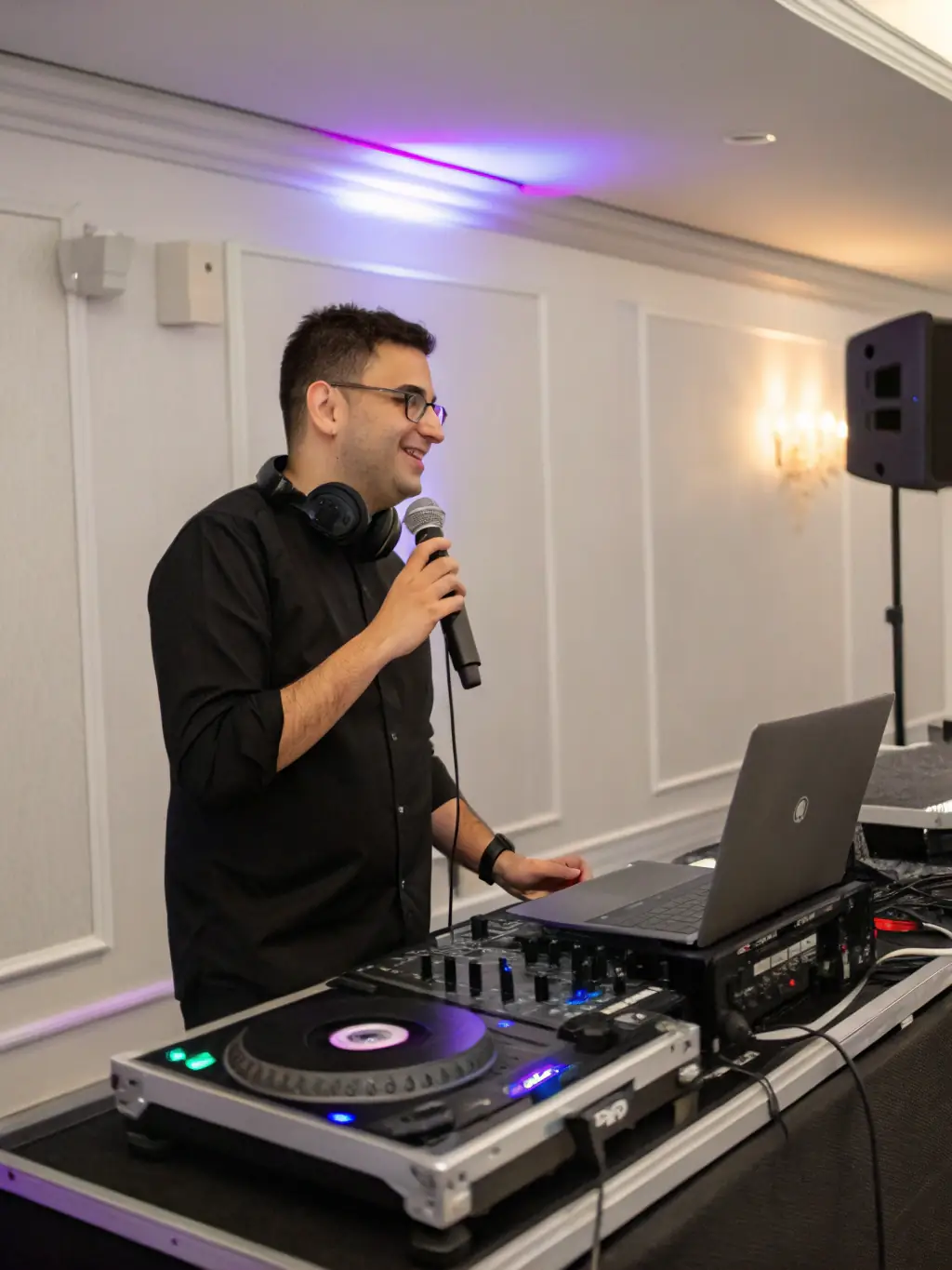 A DJ performing at a corporate event, mixing music with professional equipment and a lively crowd in the background. The lighting is dynamic and the atmosphere is energetic.