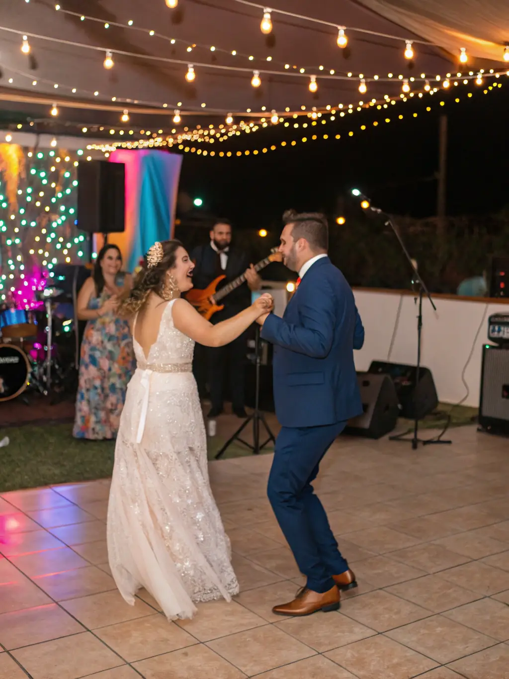 A live band performing at a wedding reception, with the bride and groom dancing in the foreground, capturing the joy and romance of the occasion.